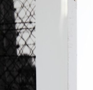 Monumental film negative photograph titled "Barbed Gate" by artist Casey McKee, depicting an inverted light-and-shadow view of the historic gate at the Auschwitz II-Birkenau concentration camp.